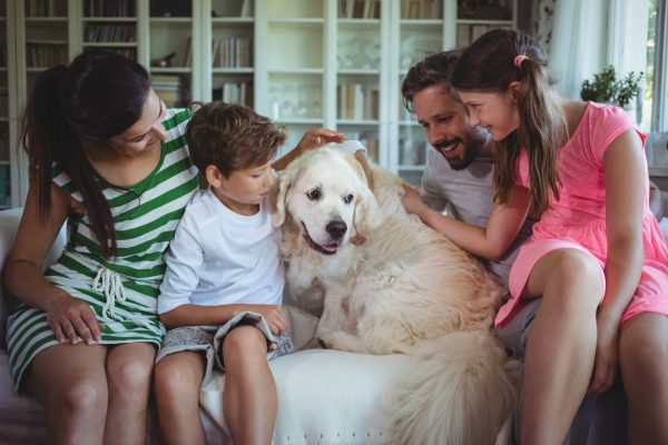 Family sitting on sofa with pet dog in living room